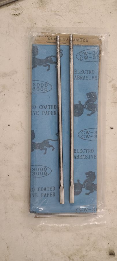A pair of hand-ground stainless steel chopsticks on a workbench